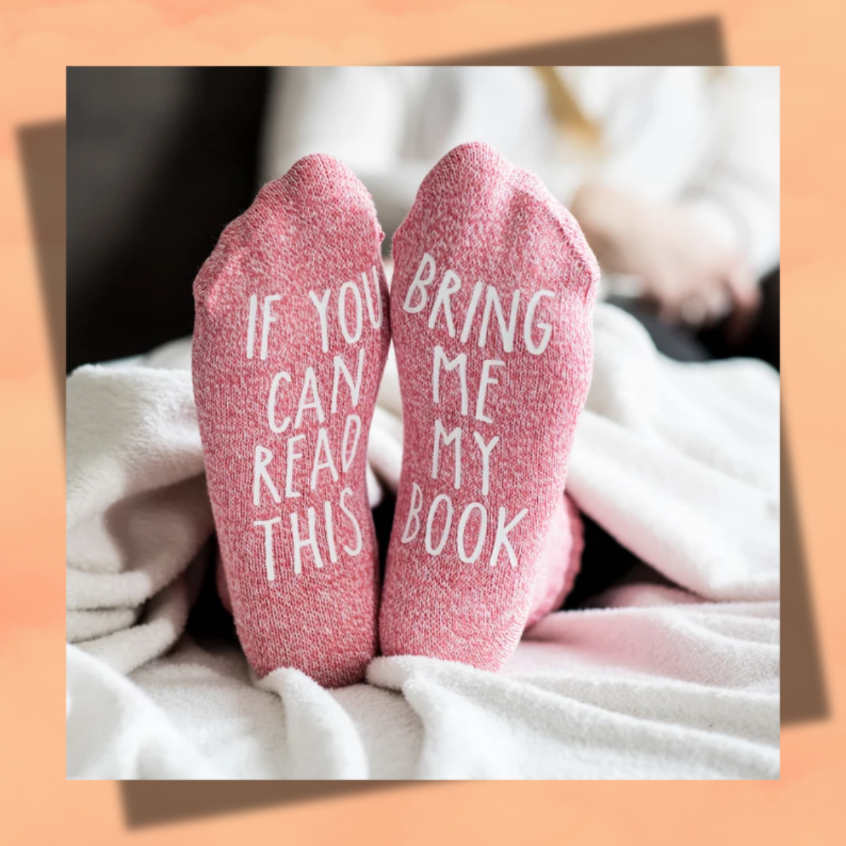 pink fuzzy socks with white text on the bottoms that reads: "if you can read this bring me my book"